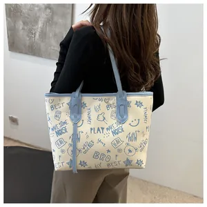 Detailed view of large cream tote bag with blue graffiti bear pattern on faux leather