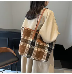 Détail de la texture en laine à carreaux et de l'anse en cuir d'un grand sac cabas