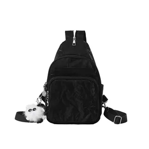Black crinkle fabric multi-pocket sling bag with a plush doll charm on a white background