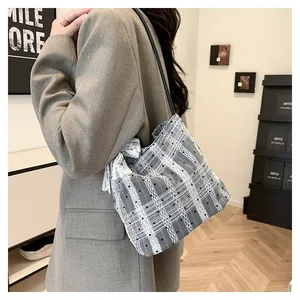 Detail of checkered bucket bag featuring white lace trim and black leather shoulder strap