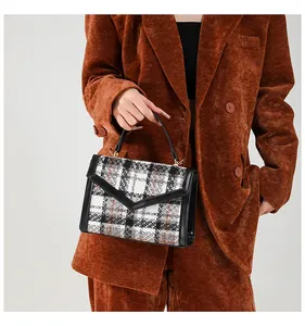 Detail van tweed schoudertas met V-vormige leren flap en gouden hardware op een model
