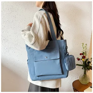 Detailansicht der hellblauen Canvas-Tasche mit Vordertasche und kleinem Münzbeutel-Anhänger