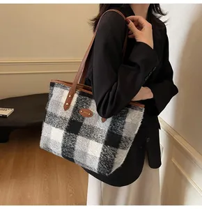 Détail d'un sac fourre-tout à carreaux avec lanières en cuir marron et rivets dorés