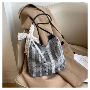 Detail of grey mesh tote bag with white lace patterns and a large decorative bow