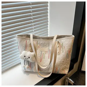 Detalle de bolso tote blanco con bordado colorido y colgante de nube junto a la ventana