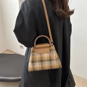 Retro plaid crossbody bag with wooden handle on model wearing a black trench coat