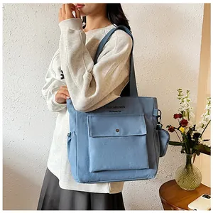 Detail der blauen Canvas-Tragetasche mit Vordertasche und stilvollem Markenschriftzug