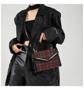 Detailweergave van de rood-groene geruite crossbodytas gedragen met een zwart pak