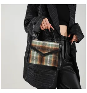 Detail van vintage geruite handtas met zwarte lederen bies en rond handvat op model
