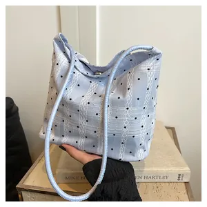 Detail of light blue plaid tote bag with black polka dots and white lace stripes