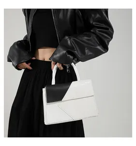 Detail of black and white handbag with crocodile and lychee textures on a model