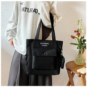 Detailansicht der schwarzen Canvas-Einkaufstasche mit Vordertasche und Mini-Geldbörsen-Anhänger