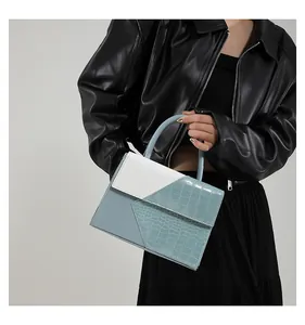 Detail of trendy color-block shoulder bag with crocodile texture and geometric flap