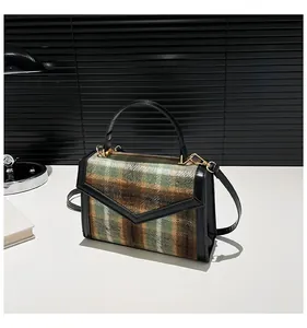 Detail van groene geruite crossbody tas met V-vormige flap en gouden metalen gesp