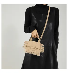 Modèle portant un sac bandoulière beige chic avec de longues franges et une poignée