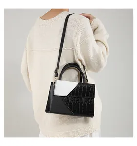 Black and white contrast leather shoulder bag shown on model with gold hardware detail
