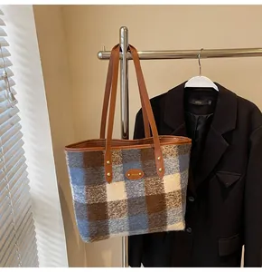 Détail d'un cabas à carreaux vintage avec lanières en cuir marron et texture tweed