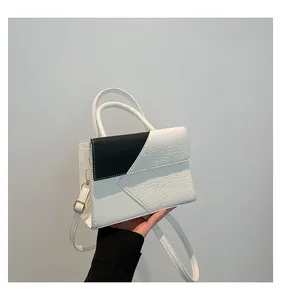Detail of black and white leather crossbody bag with crocodile texture and gold hardware