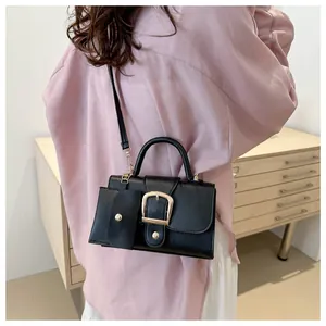 Detailed view of a black crossbody bag with gold hardware and a mini pouch attachment