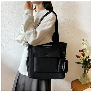 Detail der schwarzen Canvas-Tragetasche mit Druckknopftasche vorne und passender kleiner Tasche