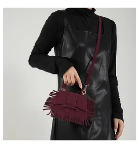 Détail du sac à main bordeaux en cuir avec de longues franges et boucle métallique