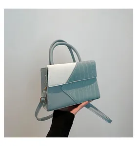 Detail of light blue and white crocodile pattern patchwork handbag with gold metal accents