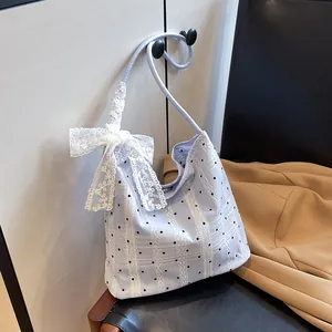 Blue plaid underarm bucket bag with lace bow and polka dots in a stylish setting