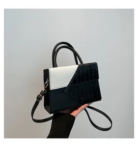 Detail of black and white leather handbag with gold metal rings and crocodile texture
