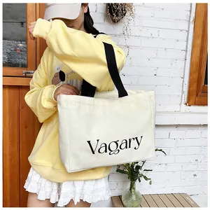 Détail d'un sac fourre-tout minimaliste en toile blanc cassé avec texte Vagary noir sur modèle