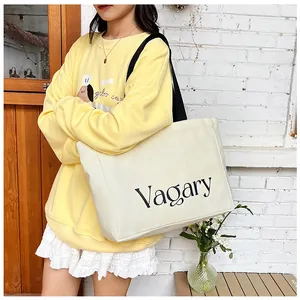 Détail du grand sac cabas en toile crème avec texte Vagary et bandoulières contrastées
