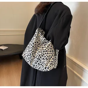 Dettaglio della borsa tote con stampa leopardata bianca e nera indossata con un cappotto nero