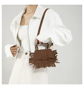 Détail d'un sac bandoulière en cuir mat marron avec franges et fermoir en métal doré