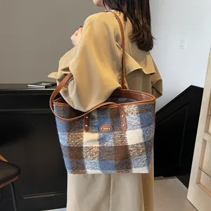 Grand sac cabas à carreaux avec anses en cuir porté par un mannequin en manteau