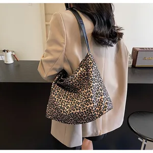 Dettaglio di una grande borsa tote leopardata con spalline in pelle nera, vista retro