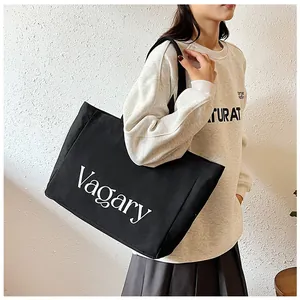 Vue détaillée du grand sac cabas en toile noire avec imprimé Vagary porté par un modèle