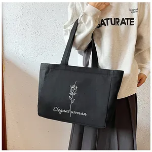 Détail du sac cabas en toile noire avec imprimé rose minimaliste et texte blanc