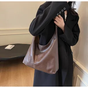 Close-up of a large dark brown tote bag with vintage leather texture and minimalist design