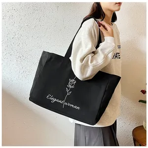 Détail du sac cabas en toile noire avec imprimé rose blanche et texte élégant