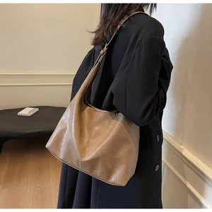 Brown large capacity tote bag with distressed matte finish on black coat model