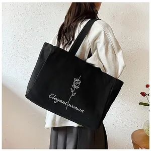 Détail du grand sac cabas noir en toile avec motif rose blanche et texte Elegant woman