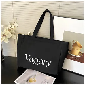 Détail d'un sac cabas en toile noire avec imprimé Vagary blanc sur un bureau épuré