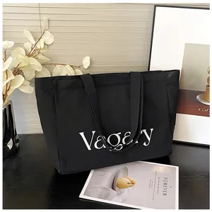 Détail du lettrage Vagary sur le grand sac cabas en toile noire avec larges anses