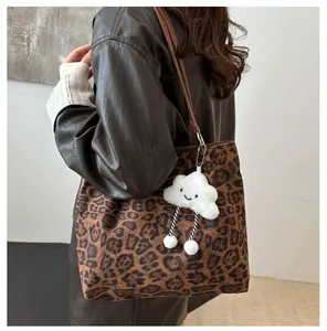 Détail d'un sac cabas imprimé léopard avec pendentif nuage en peluche et bandoulière en cuir
