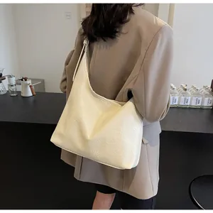 Detailed view of cream-colored hobo tote bag with textured leather on shoulder