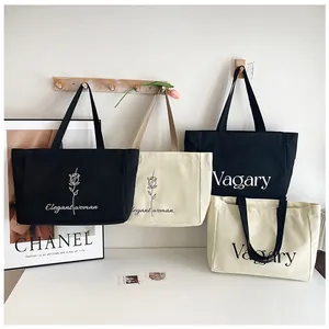 Détail de sacs fourre-tout en toile avec imprimés rose et lettres en noir et beige