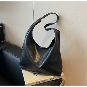 Detailed macro view showing the oil-wax texture and vertical seam of the black hobo bag
