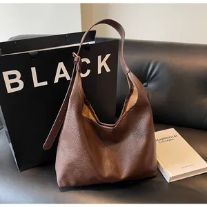 Close-up of deep brown vintage tote bag with wrinkled texture on black sofa