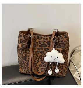 Détail d'un sac cabas léopard avec un pendentif nuage en peluche blanc mignon