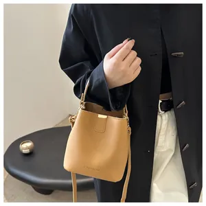 Détail du sac seau marron clair avec ferrures dorées et logo FASHION embossé