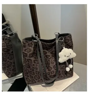 Vue détaillée du sac cabas léopard avec pendentif nuage en peluche et anses en cuir